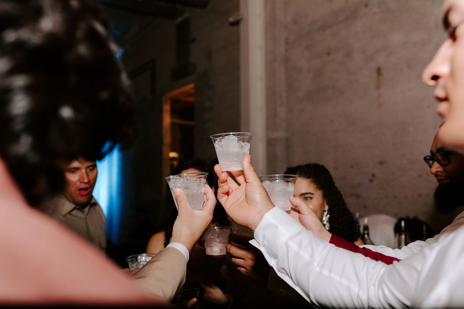 People raising shot glasses together in a celebratory toast at an event.