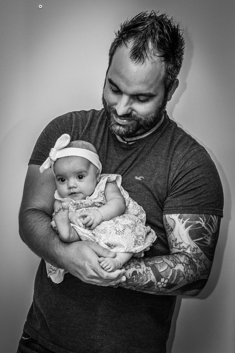 A series of black and white photos showing tender moments between a father cradling and interacting with his baby.