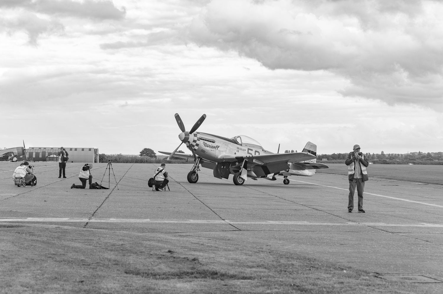 World War II era P-51 Mustang fighter aircraft on display at airshow with onlookers nearby.