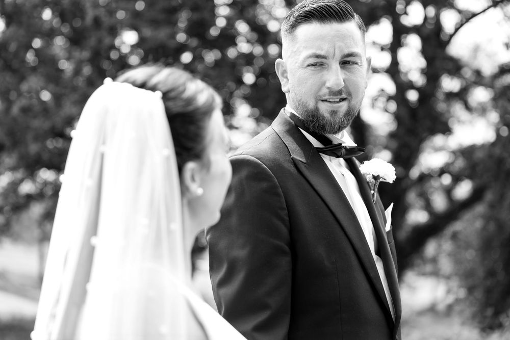 Black and white photo of the groom smiling warmly at the bride during their portrait session.