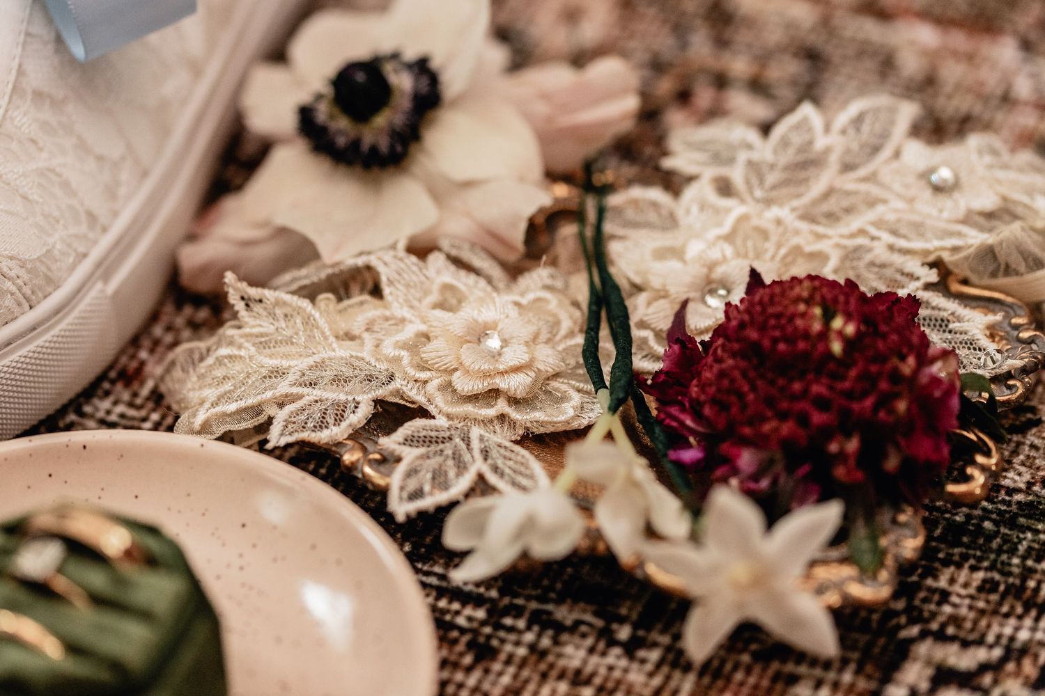 Flat lay of embroidered bridal lace, purple and cream flowers, gold tray, and wedding rings—vintage wedding detail inspiration.