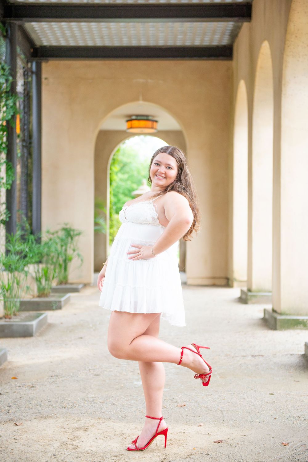 A sequence of 5 coordinated photos showing a person in a white dress and red heels posing under arched columns.