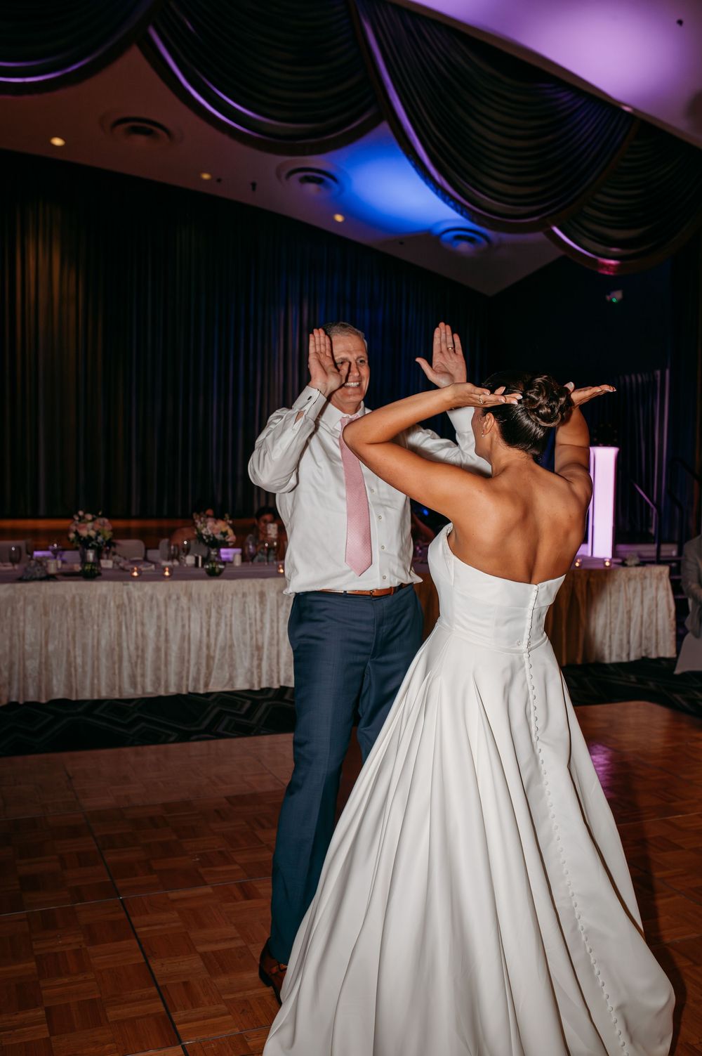 Wedding couple strikes synchronized dance pose during reception celebration.