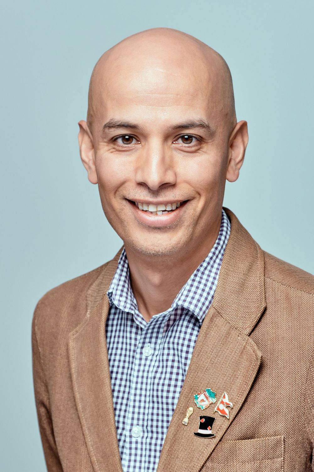 Professional headshot series of person in blue checkered shirt and tan blazer against light blue background.