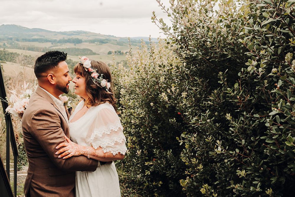 A romantic outdoor moment shared between couple in lush green countryside wearing neutral colored attire.