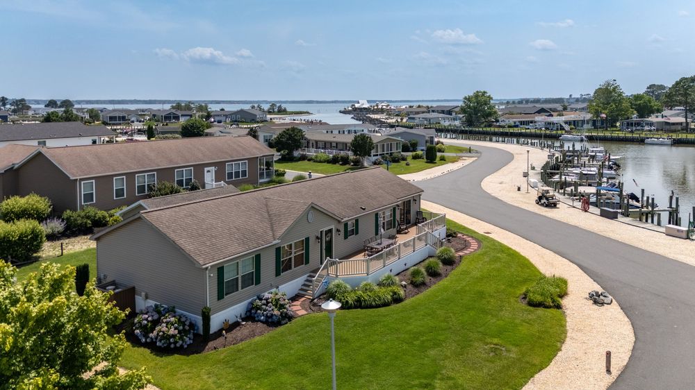 Panoramic aerial view of waterfront houses and boat docks along the shoreline of a coastal residential community.