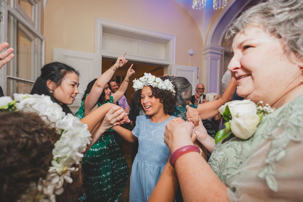 Joyful wedding reception dance party with guests on the dance floor enjoying an upbeat celebration.