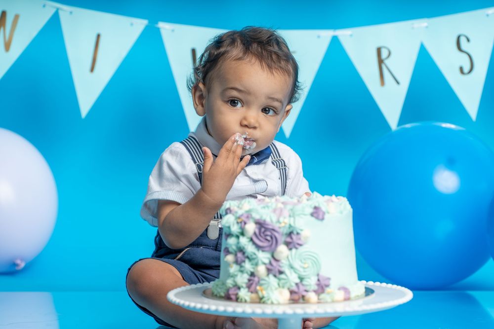 A festive cake smash photography setup with blue and white decorations and party bunting.