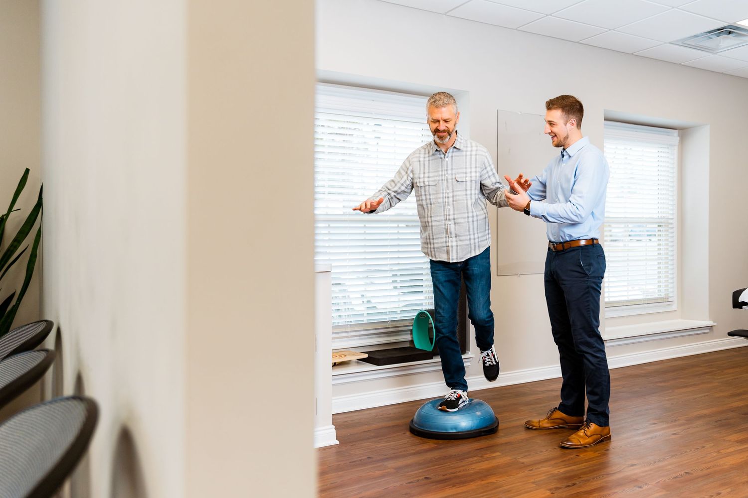 Michigan Commercial Videographer captures Physical therapist assisting senior patient with balance exercise on stability disc.