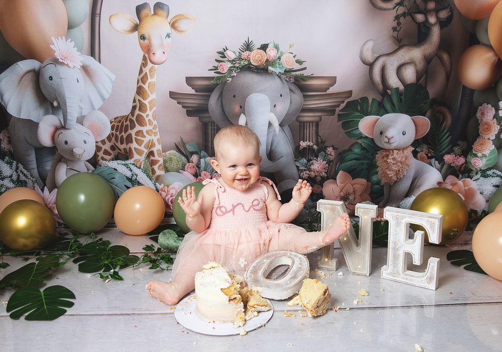 A rustic cake smash photo session setup with grey elephants, neutral balloons, and gold 'ONE' letters. During photoshoot in London, Bexley.