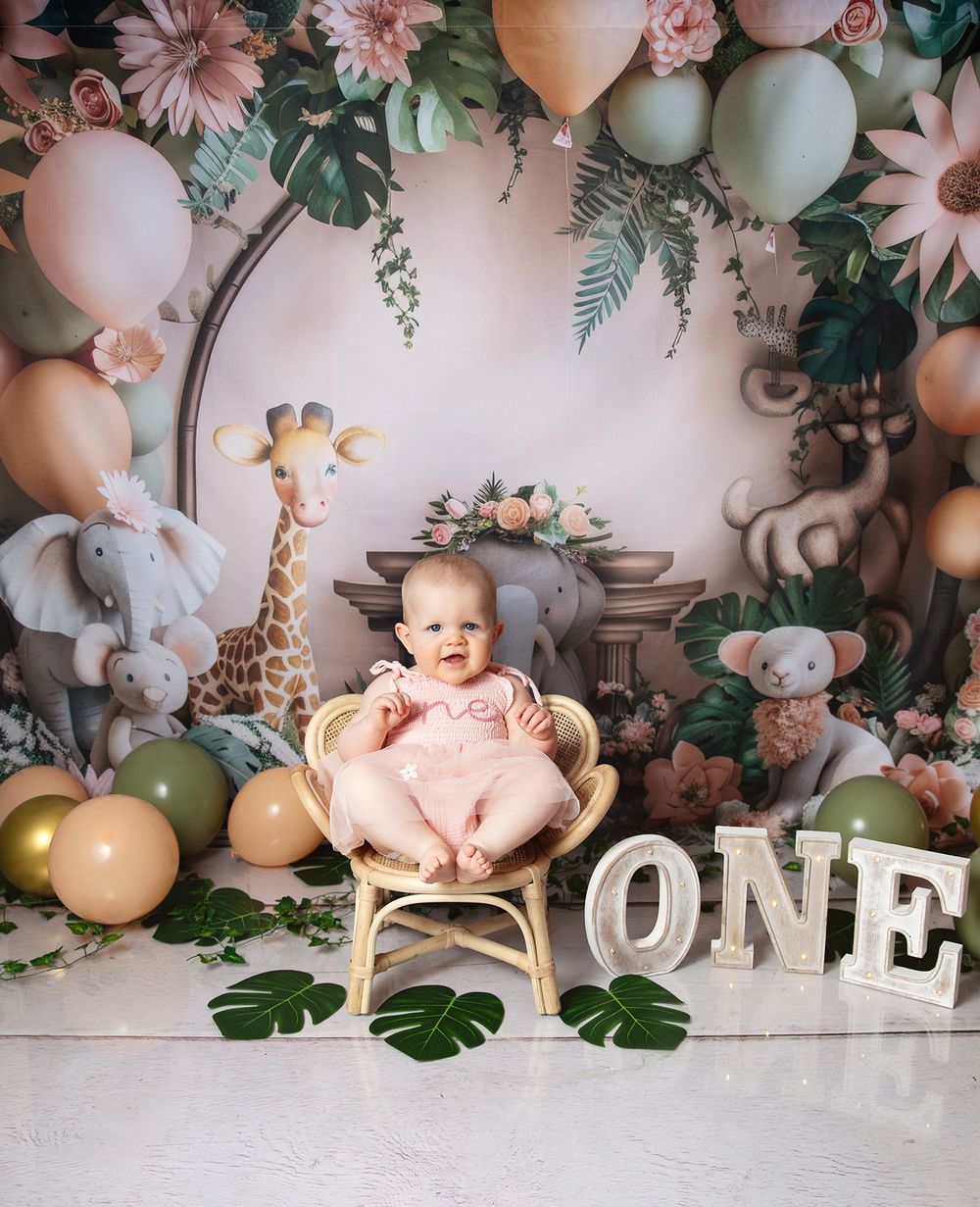 A festive first birthday setup with balloons, stuffed animals, floral decor and 'ONE' lettering against a pastel backdrop in London