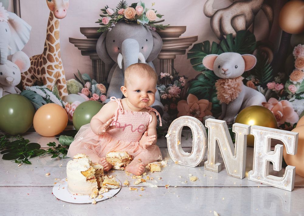 First birthday party scene with balloon arch, floral arrangements, and rustic decorations in soft pink tones. During photoshoot in London