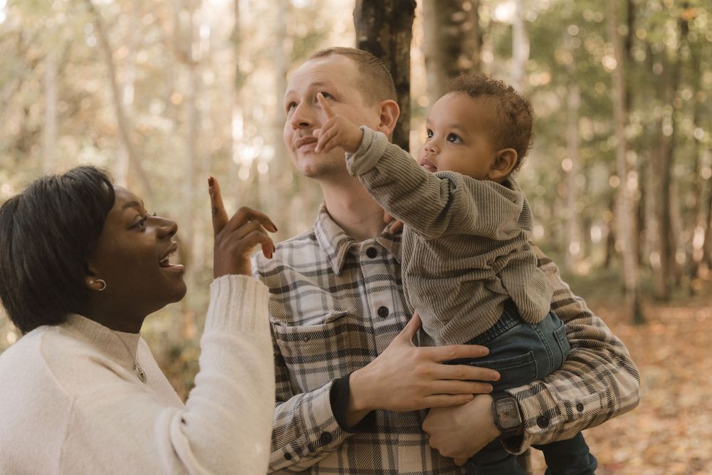 A family enjoying outdoor moments together in a park with autumn leaves in the background.