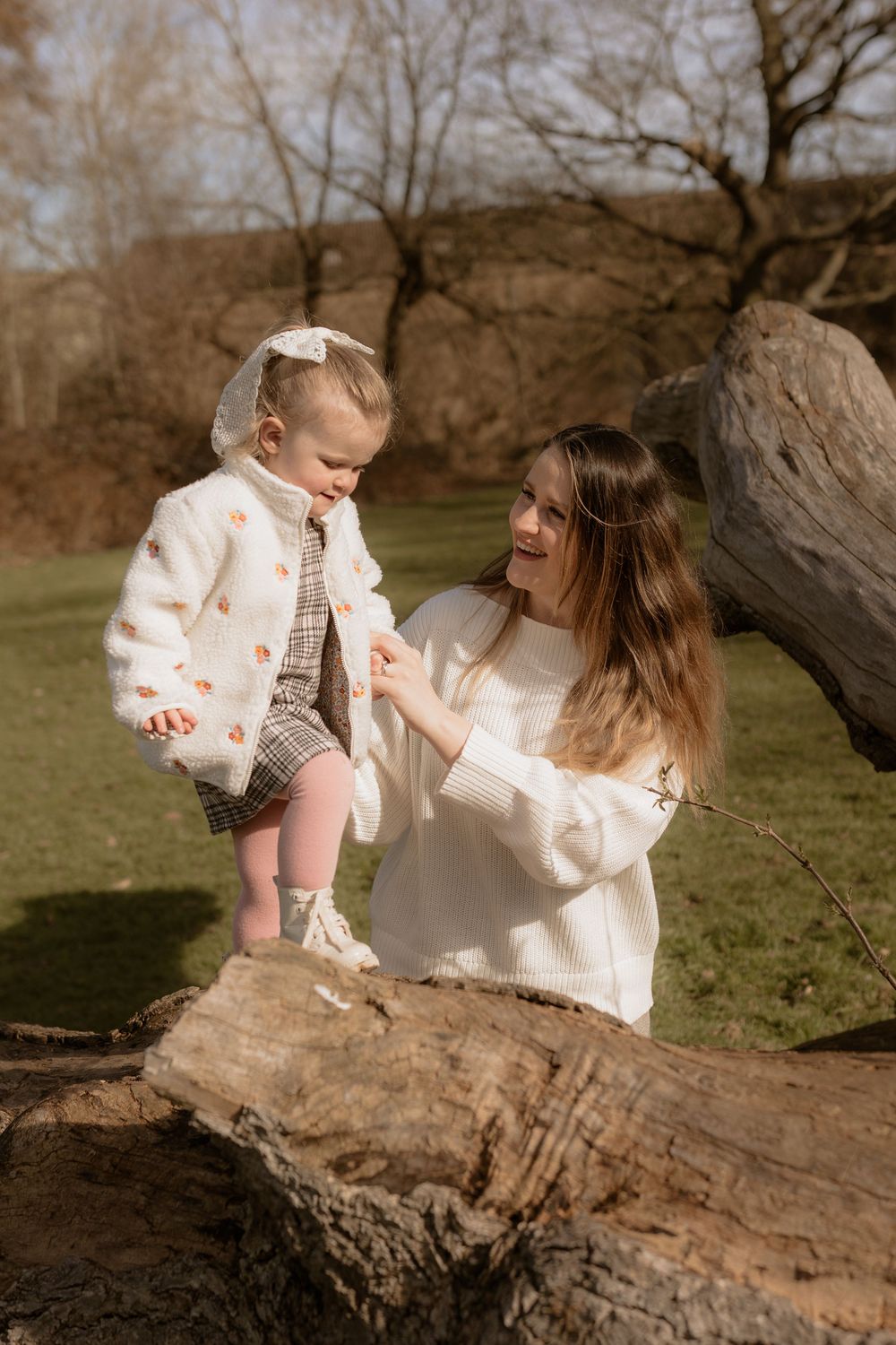 Sweet moment captured in sepia tones as child and parent share time together on a fallen log in a natural setting.