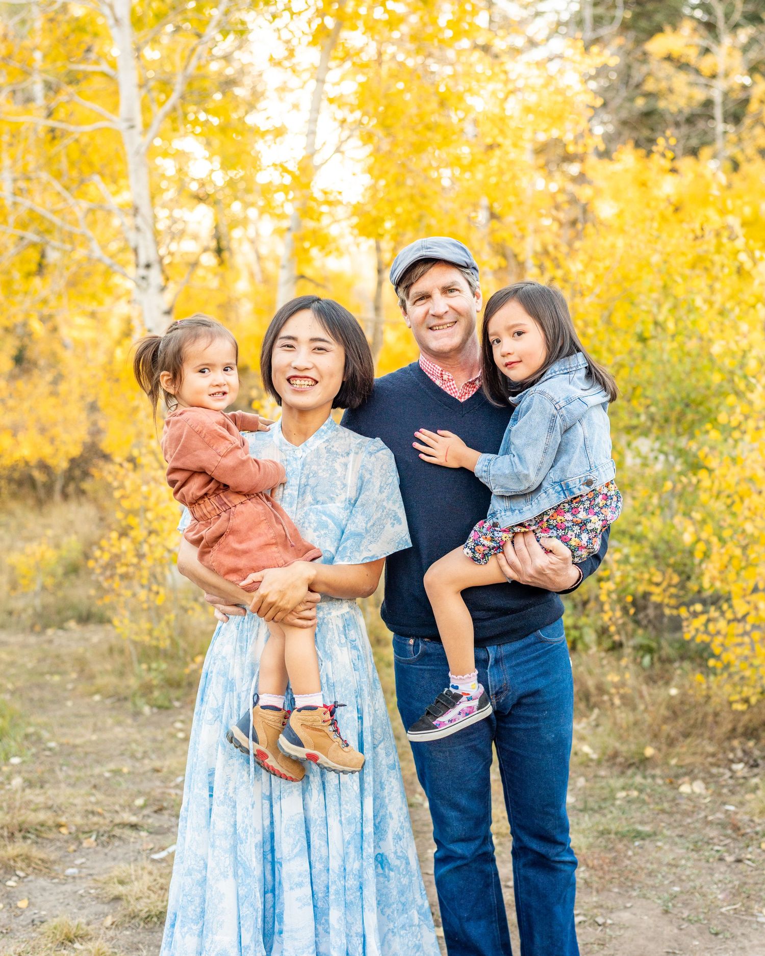 Family enjoying autumn scenery with golden aspen trees in background during outdoor portrait session.