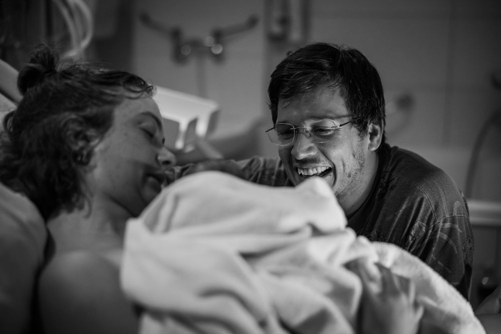 dad with joyful expression looking at his newborn bay and wife birth photographer cape town