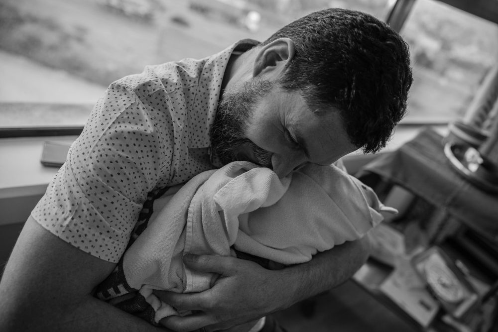 Dad embracing newborn baby for the first time Birth Photographer Cape town