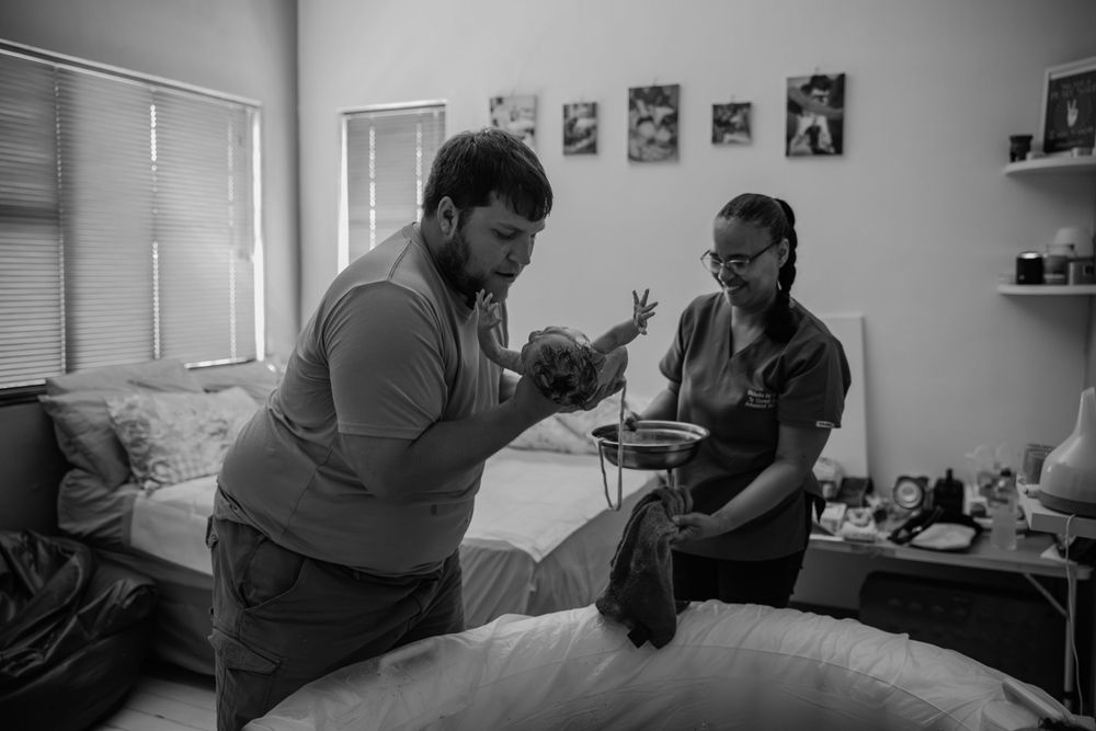 dad holding newborn for the first time cape town birth photographer By Grace Photography