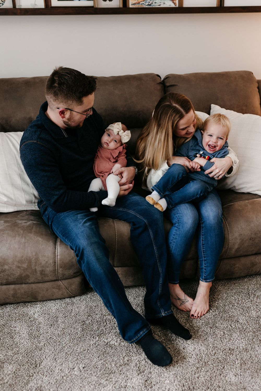 A family relaxes together on a brown leather couch in a cozy living room.