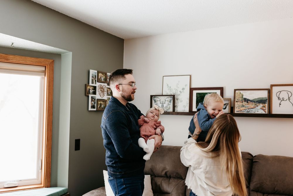 Happy family shares joyful moment together in cozy living room with framed photos on wall.