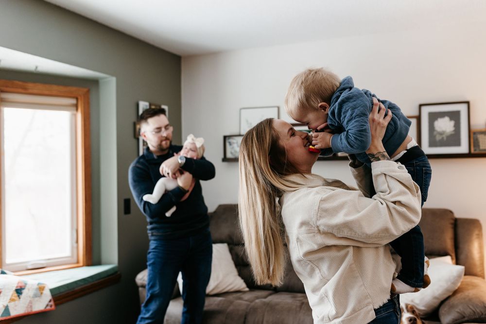 Parents share a joyful moment with their baby in a cozy living room setting.