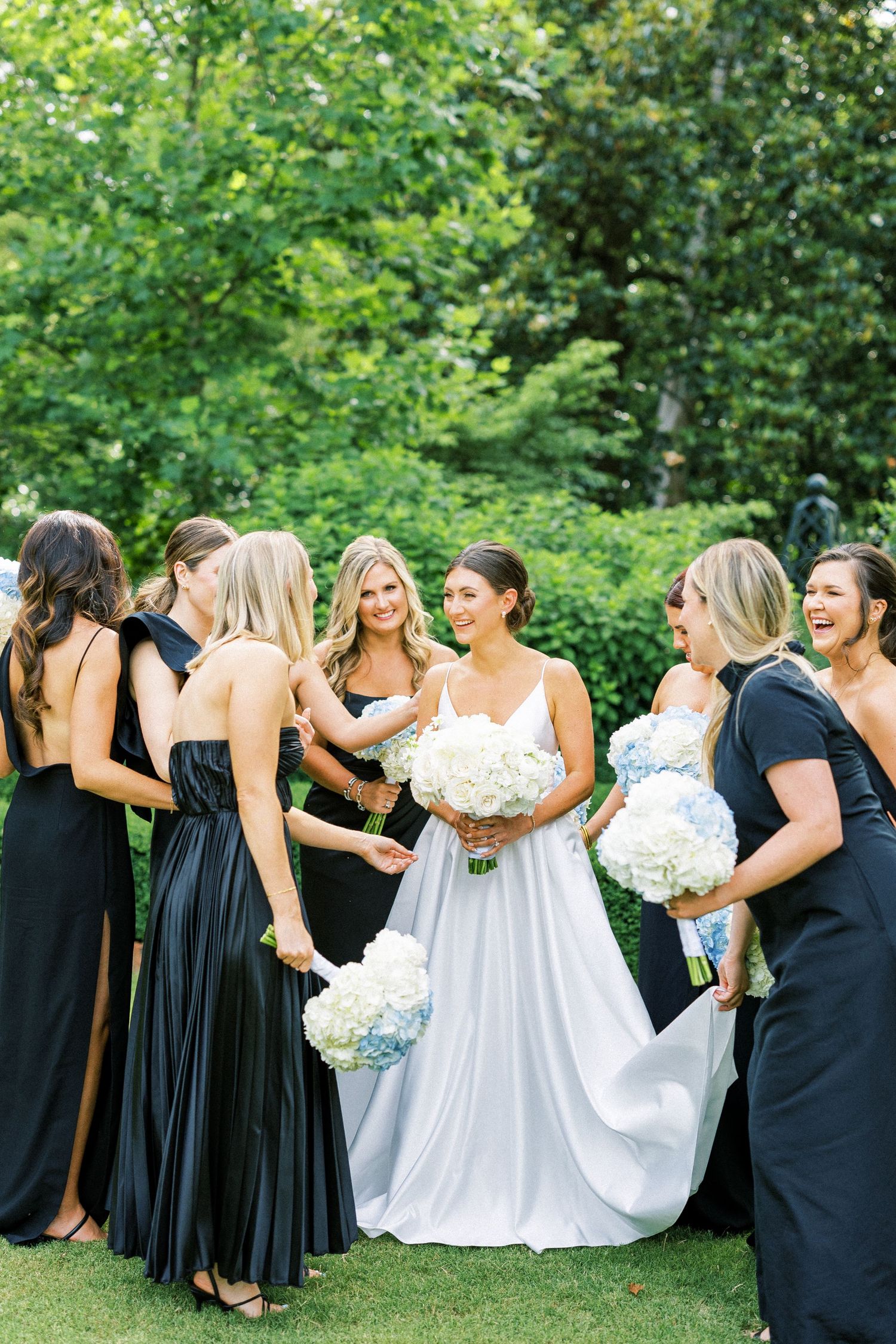 Bridal party in navy dresses and white gowns posing together outdoors.