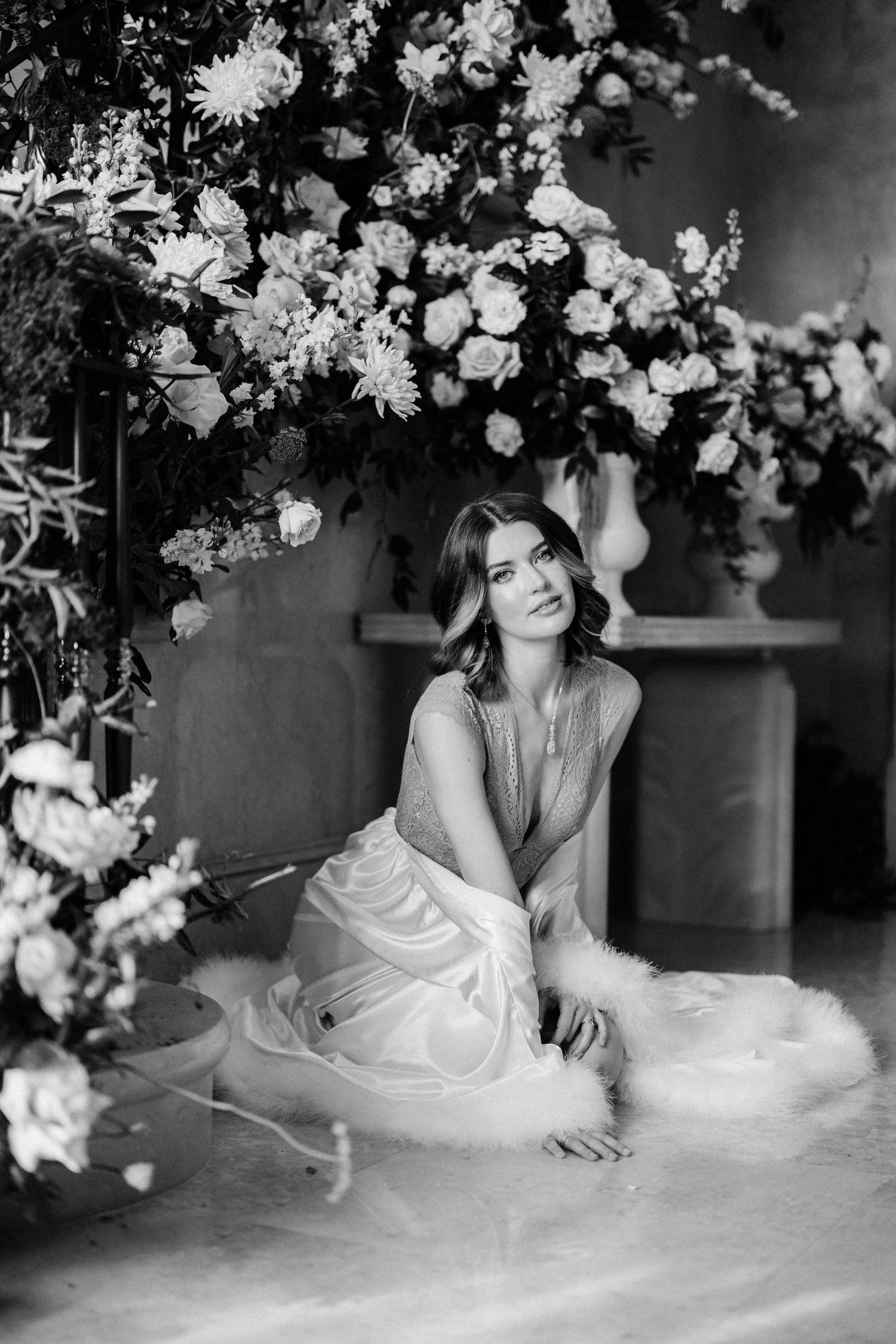 Black and white portrait under floral arch with soft dreamy aesthetic.