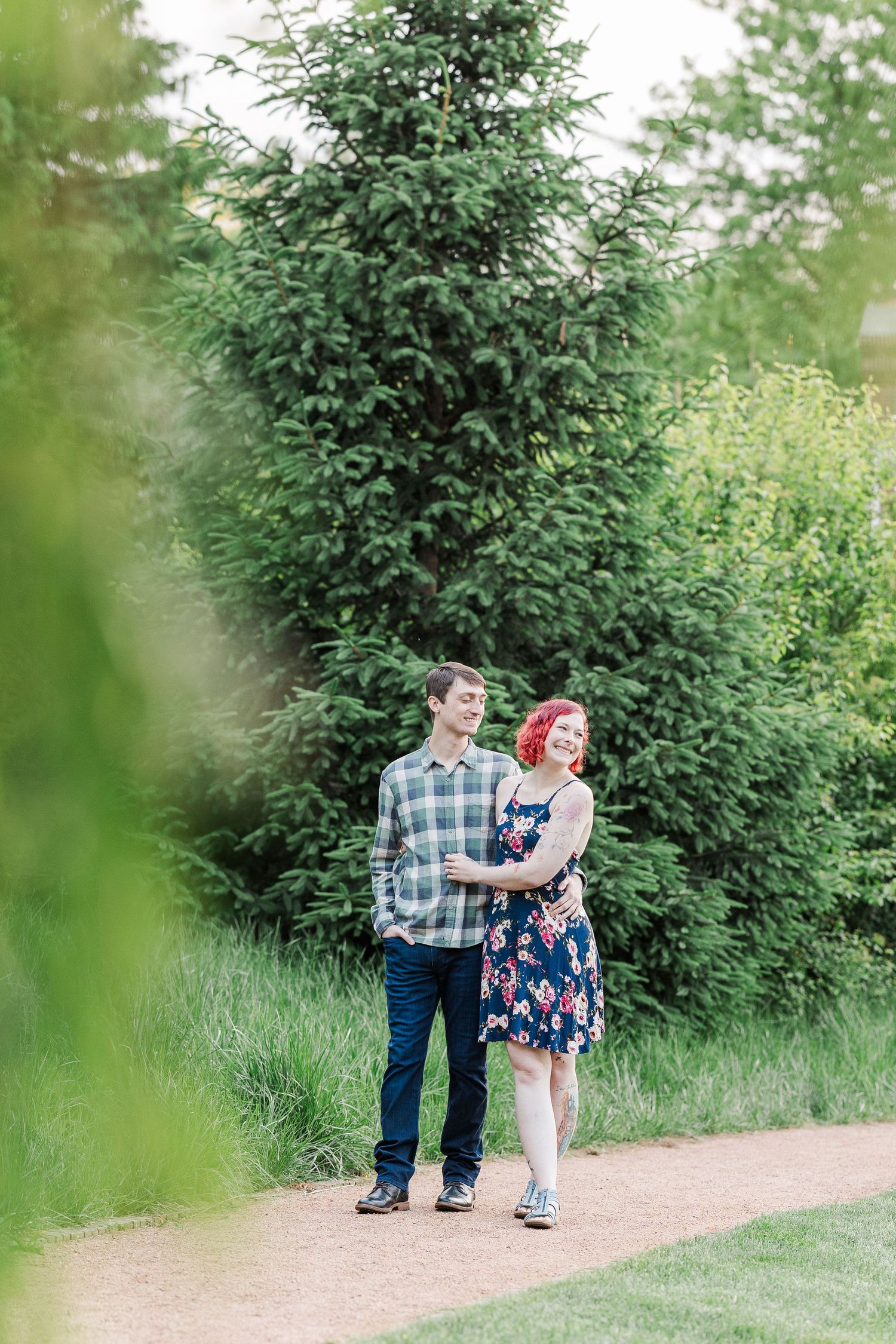 A couple walks together on a garden path surrounded by lush greenery and tall evergreen trees at Cantigny Park