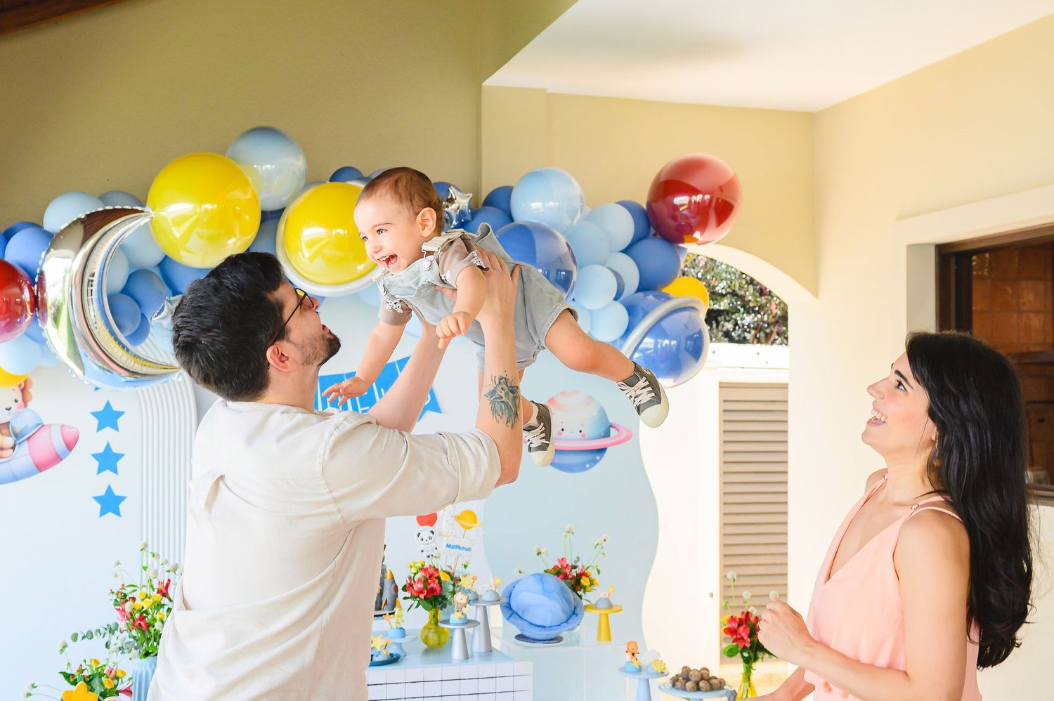 A cheerful celebration decorated with blue and yellow balloons features happy people at a baby-themed party.