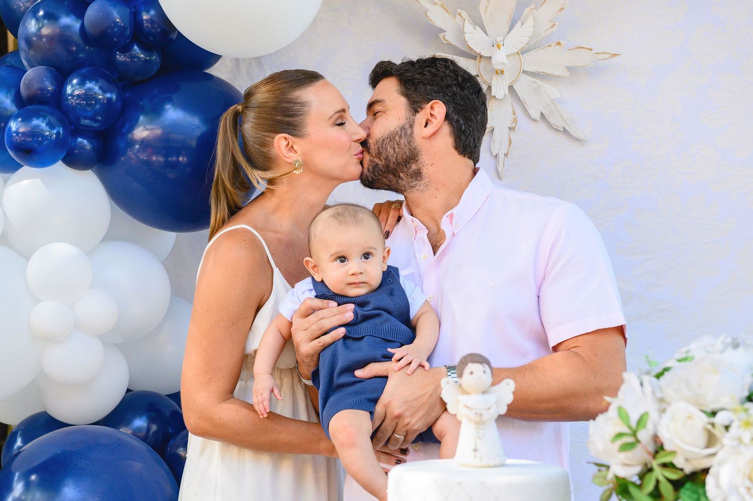 Family celebrates special moment with blue and white balloon decorations and floral arrangements at festive party setting.