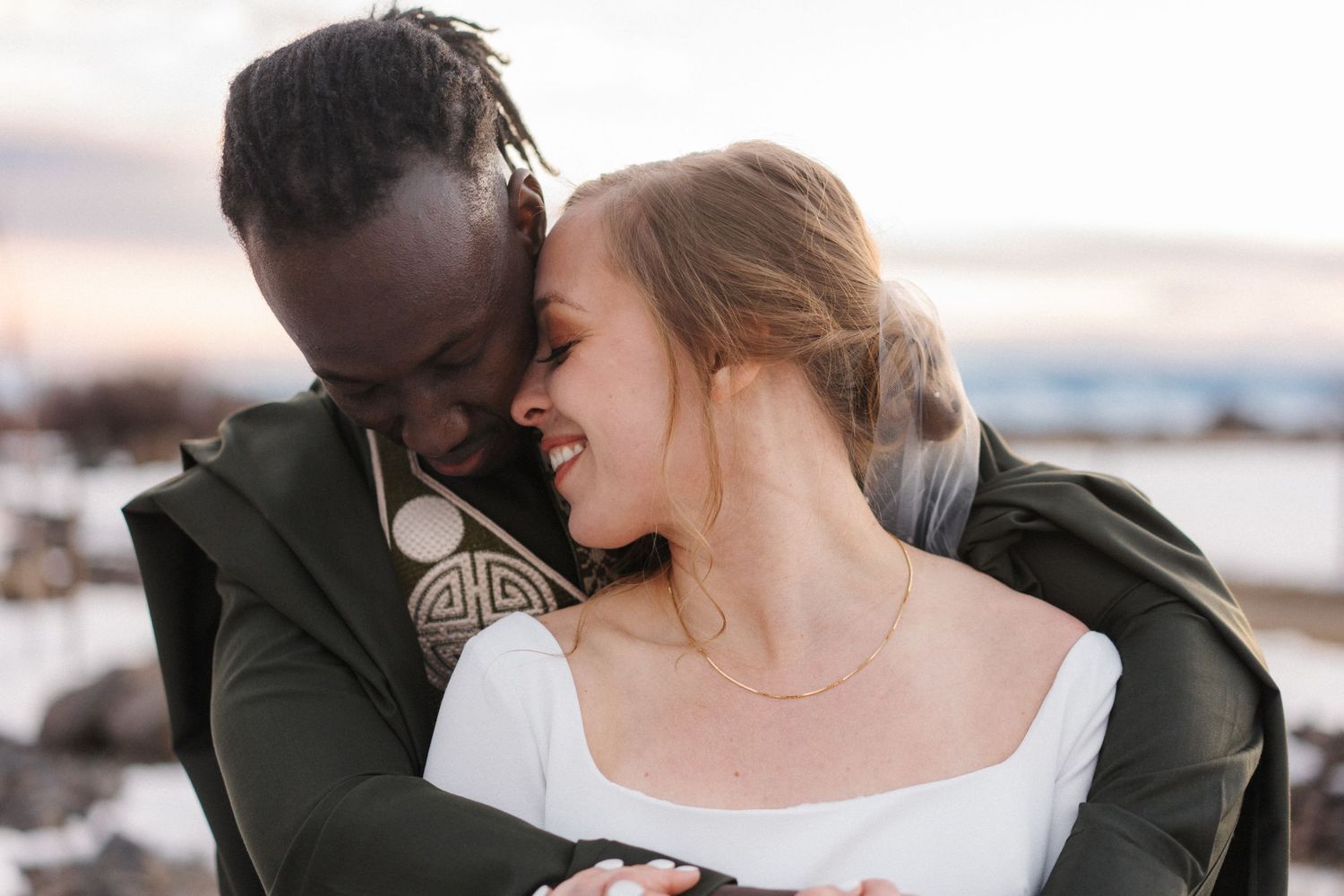 A couple shares an intimate moment embracing on the beach during sunset.