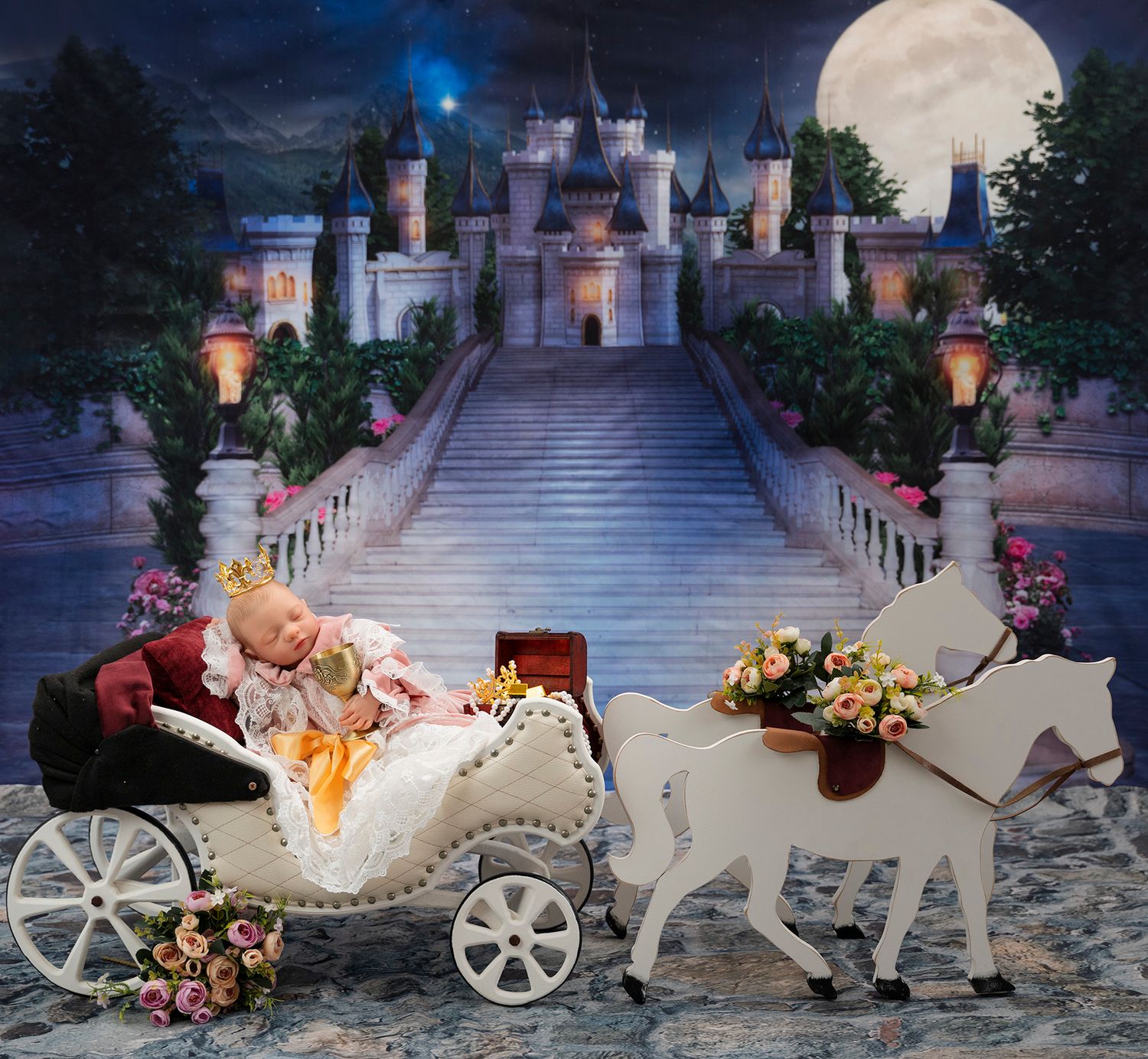 Fairytale newborn photo with castle backdrop, white carriage and moonlit scene.