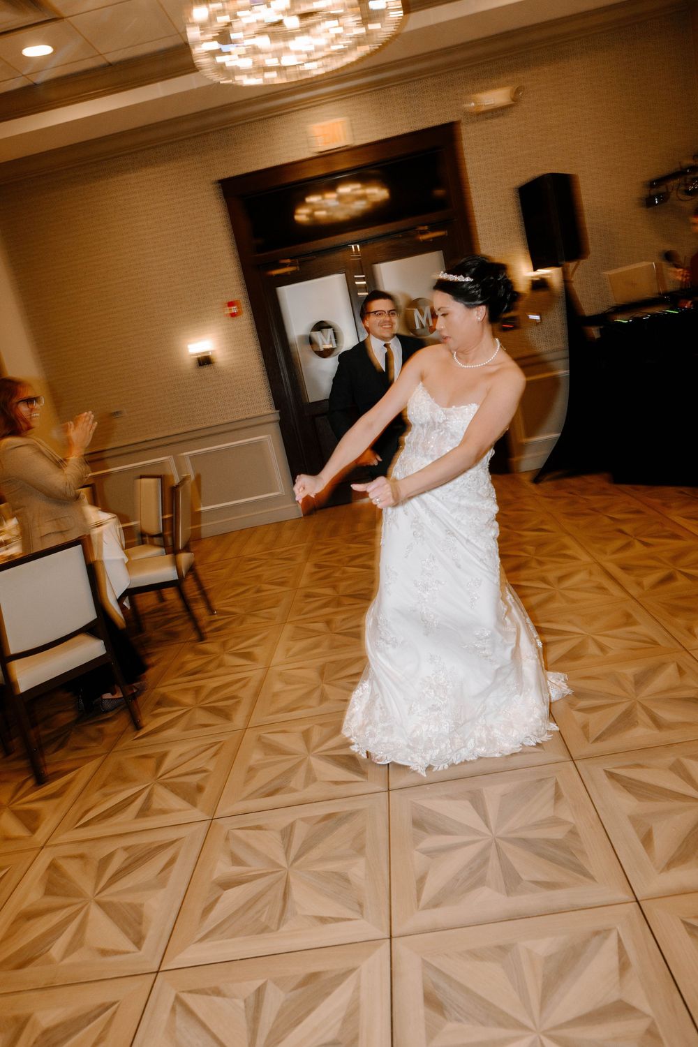 Dancing at a wedding reception on a patterned ballroom floor with elegant lighting and decor.