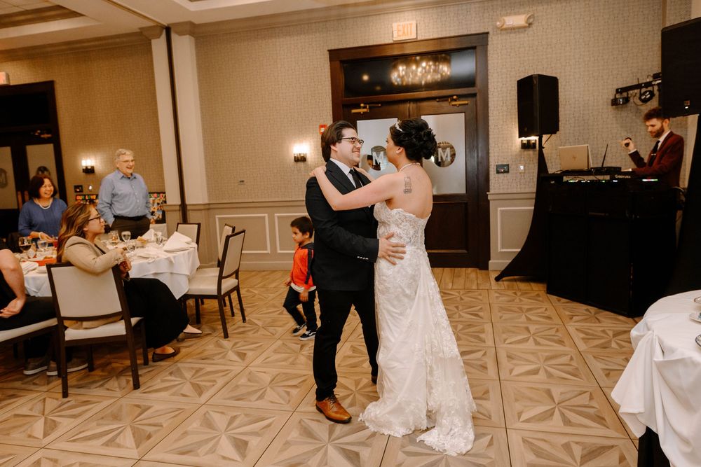 Two people share an intimate dance together in an elegant ballroom with patterned carpet and mood lighting.