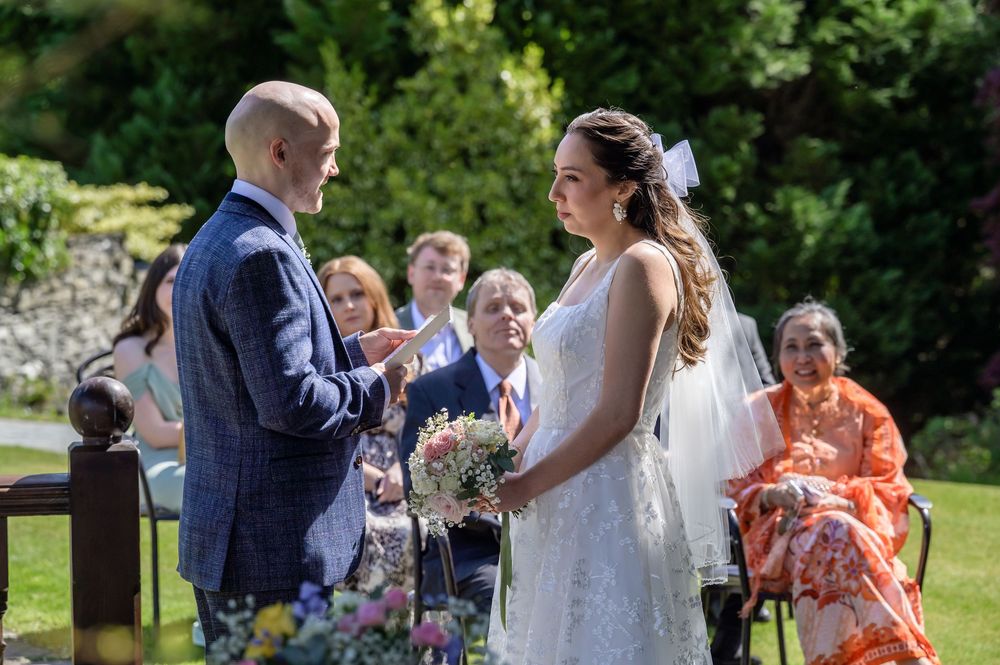 Groom reading personal vows to bride during outdoor wedding at Cragwood Country House