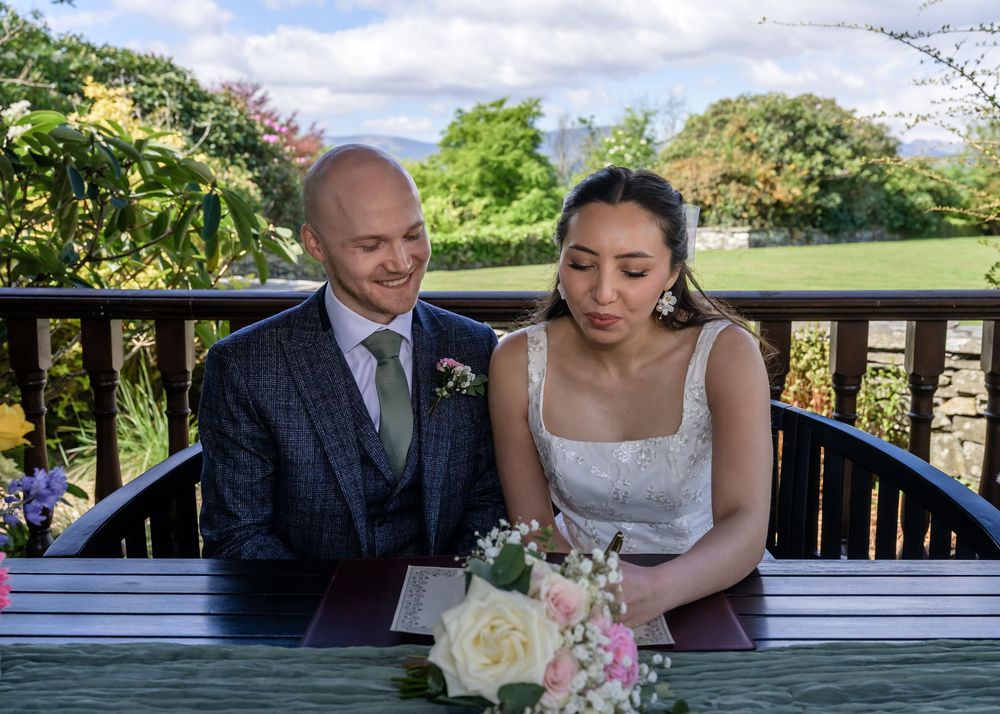 Bride and groom signing wedding schedule in gazebo at Cragwood Country House Hotel