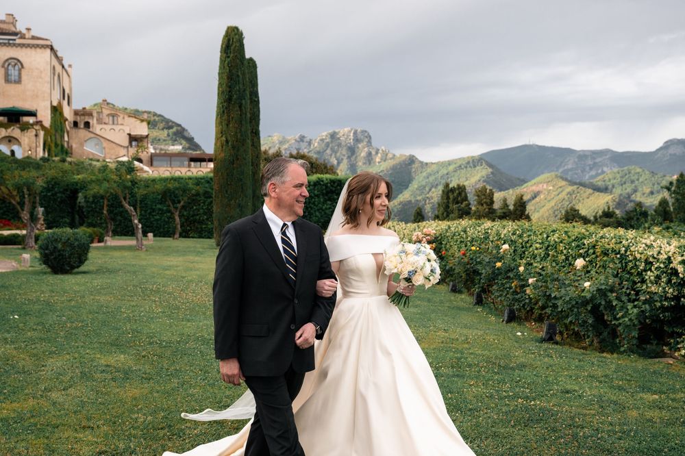 Classical wedding couple walking through garden with mountain landscape in background.