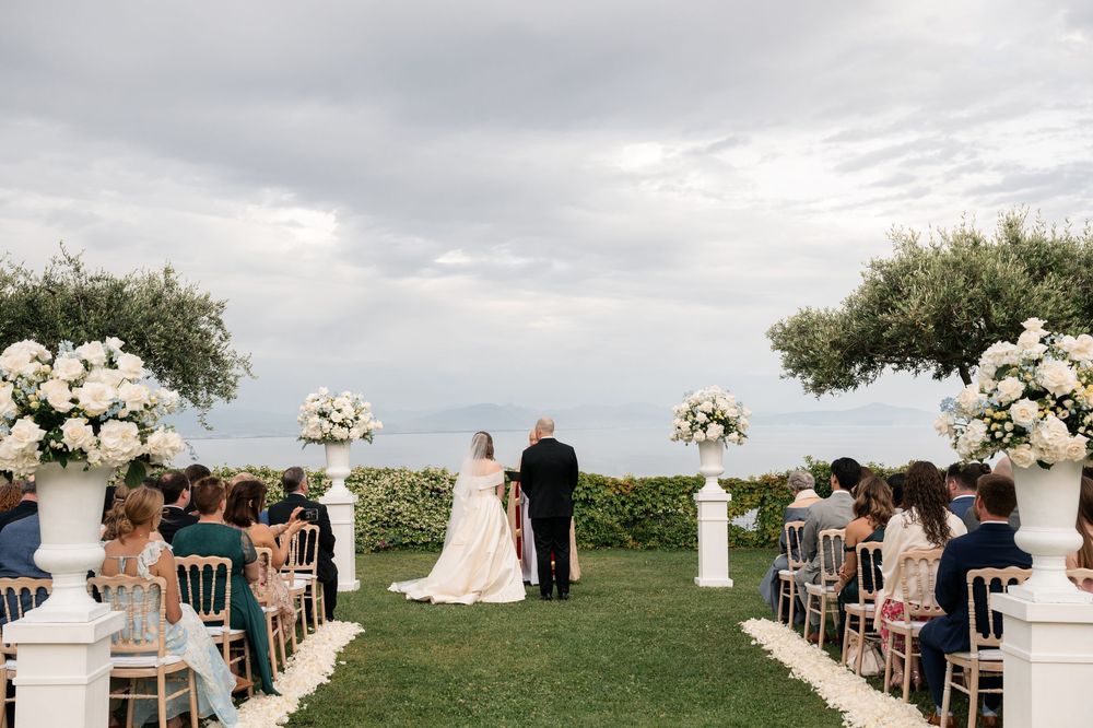 An outdoor wedding ceremony setup with white chairs and floral arrangements overlooking the ocean.
