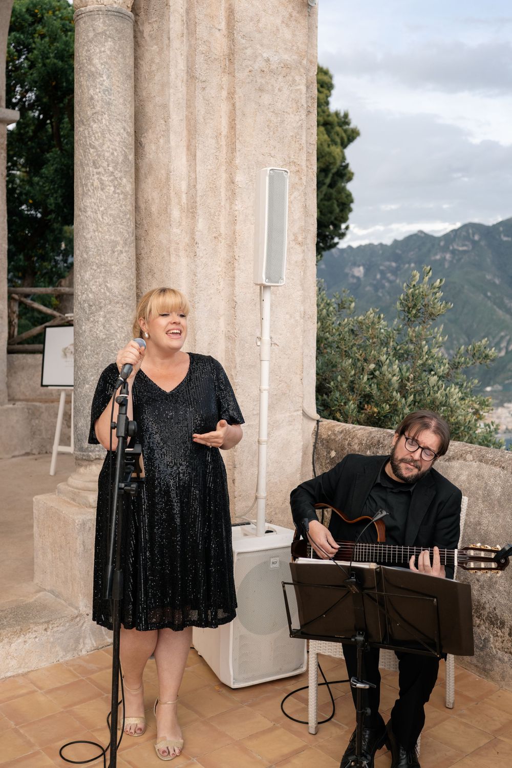 Musicians performing at an outdoor venue with mountains in the background.