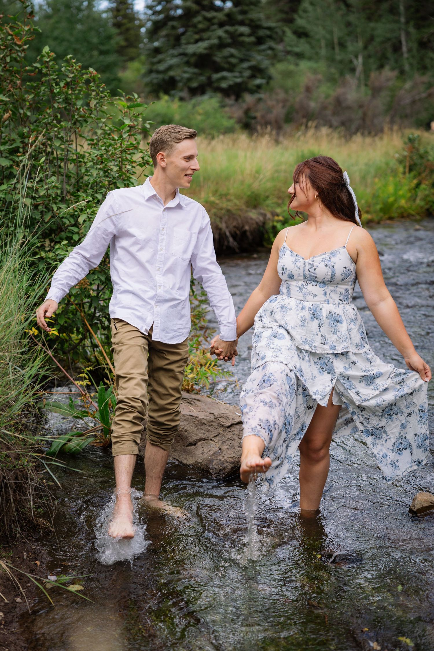 A couple enjoys a playful moment together while wading in a creek surrounded by lush greenery. Knoxville Tennessee.