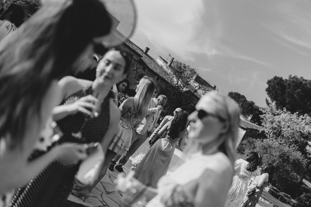 Wedding guests smile and celebrate during an outdoor reception on a sunny day.