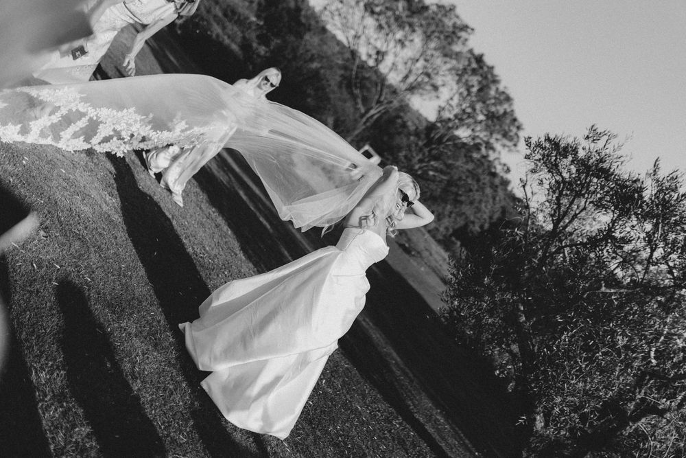 Wedding dress veil flowing dramatically in the wind during an outdoor photo session.