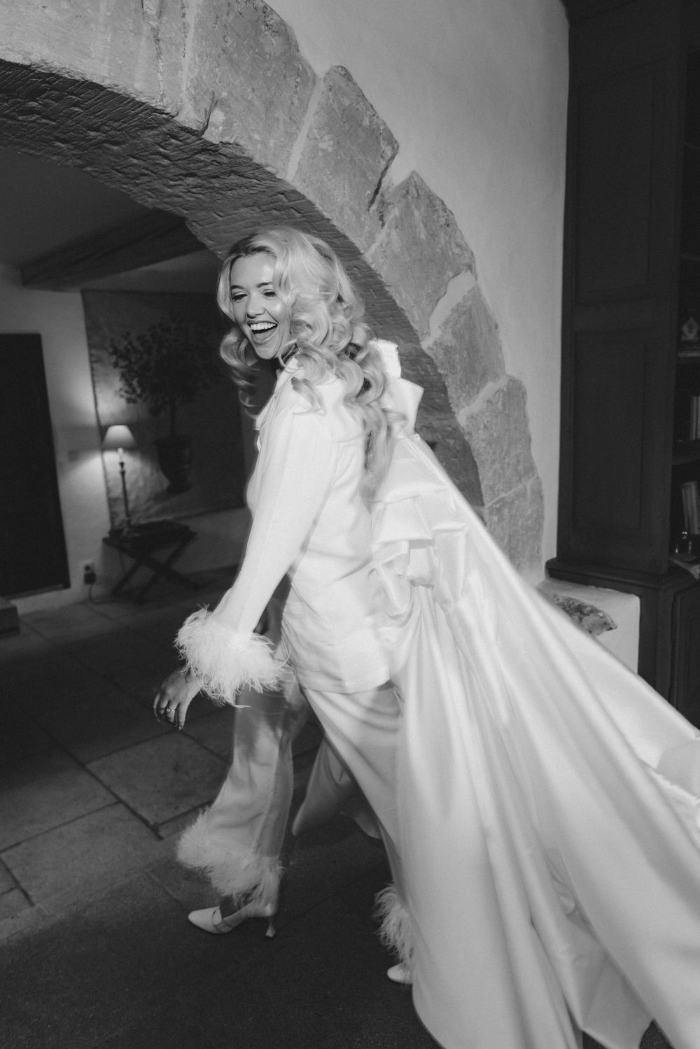 Black and white photos showing bride in elegant white dress posing near stone archway.