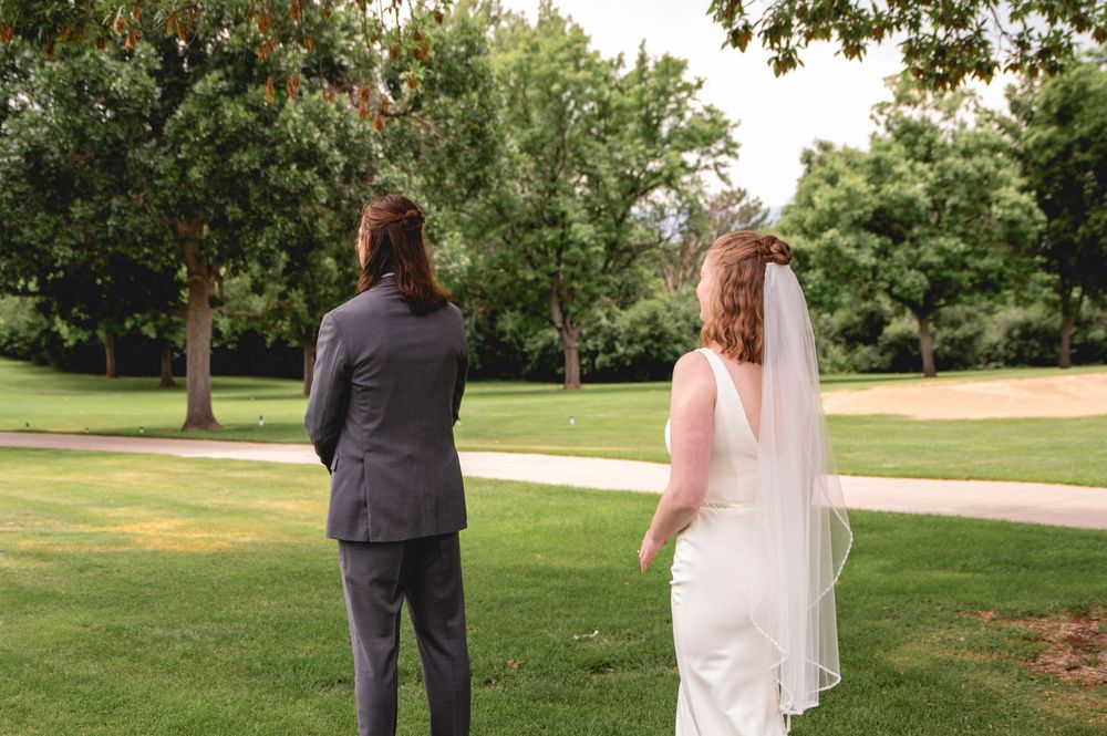 Bride and groom walk hand in hand across a lush green lawn on their wedding day during an outdoor ceremony.