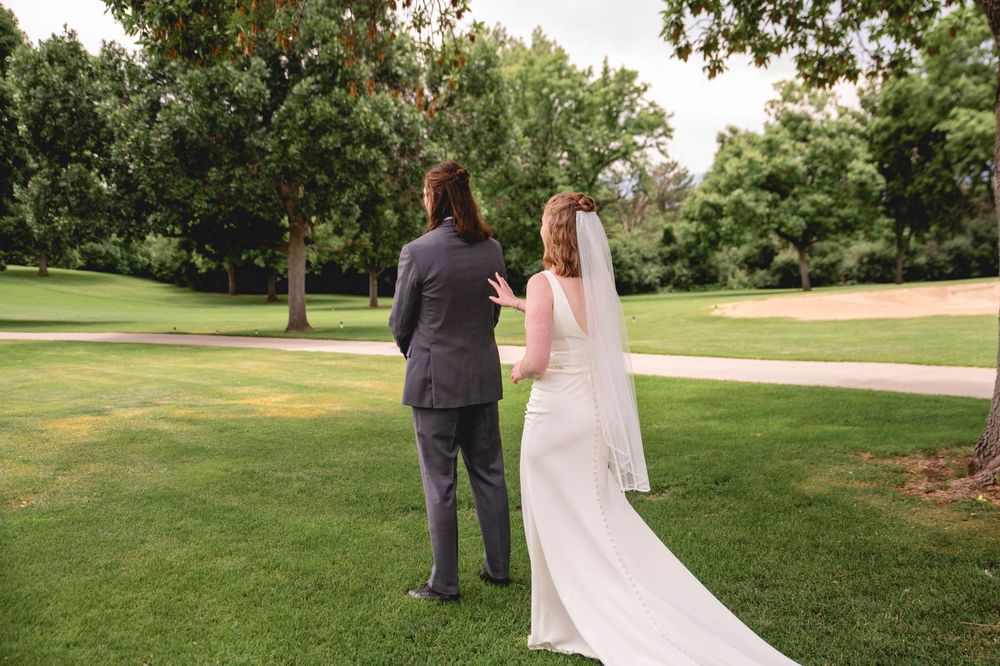 A couple walks hand-in-hand through a lush green garden path as they celebrate their outdoor wedding.