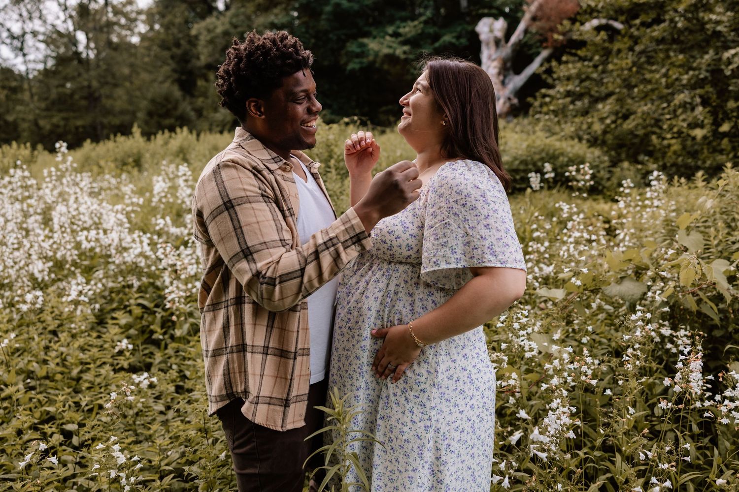 A couple shares a joyful moment together in a wildflower meadow during a warm summer evening.