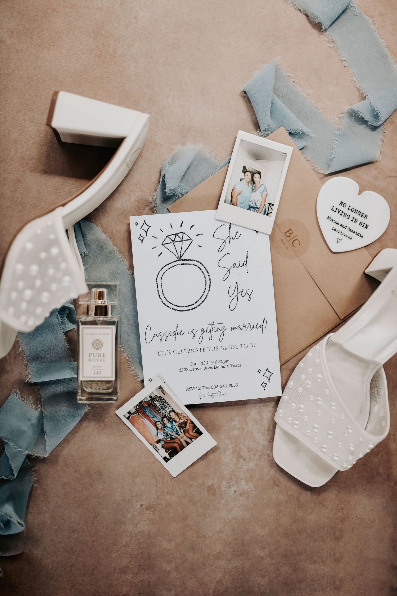Overhead flat lay with perfume bottle, heirloom rings, and vow books