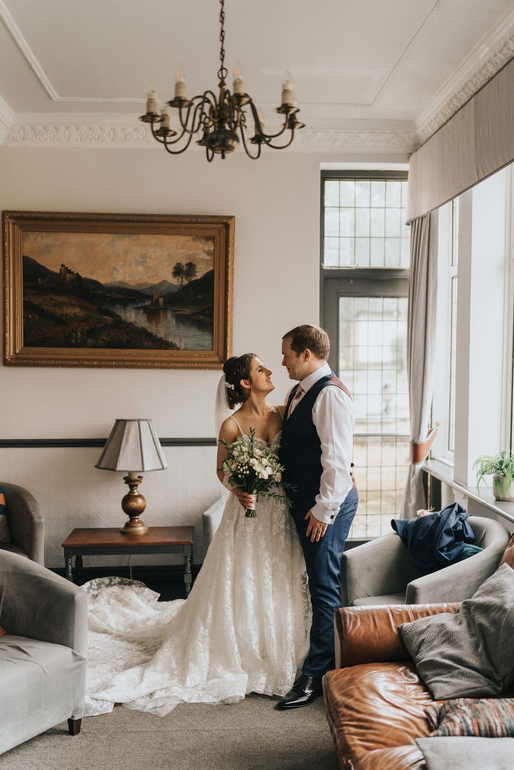 A romantic moment in an elegant living room with vintage decor, featuring a chandelier and landscape painting on the wall at Cave Castle.