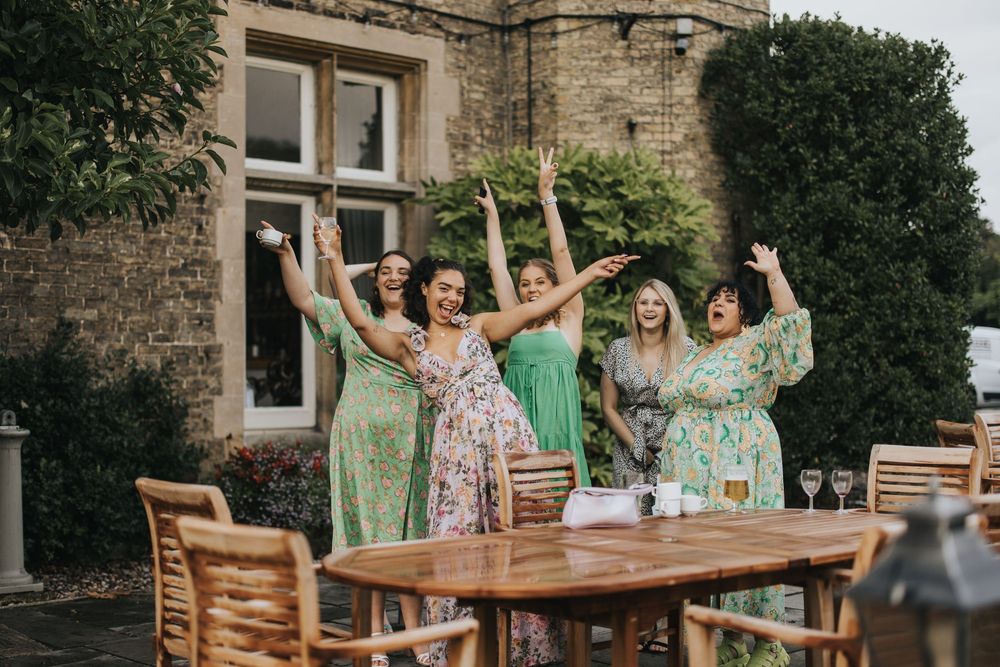 A group of people in pastel floral dresses celebrate joyfully at an outdoor wedding party at Cave Castle - taken by Grimsby photographer.