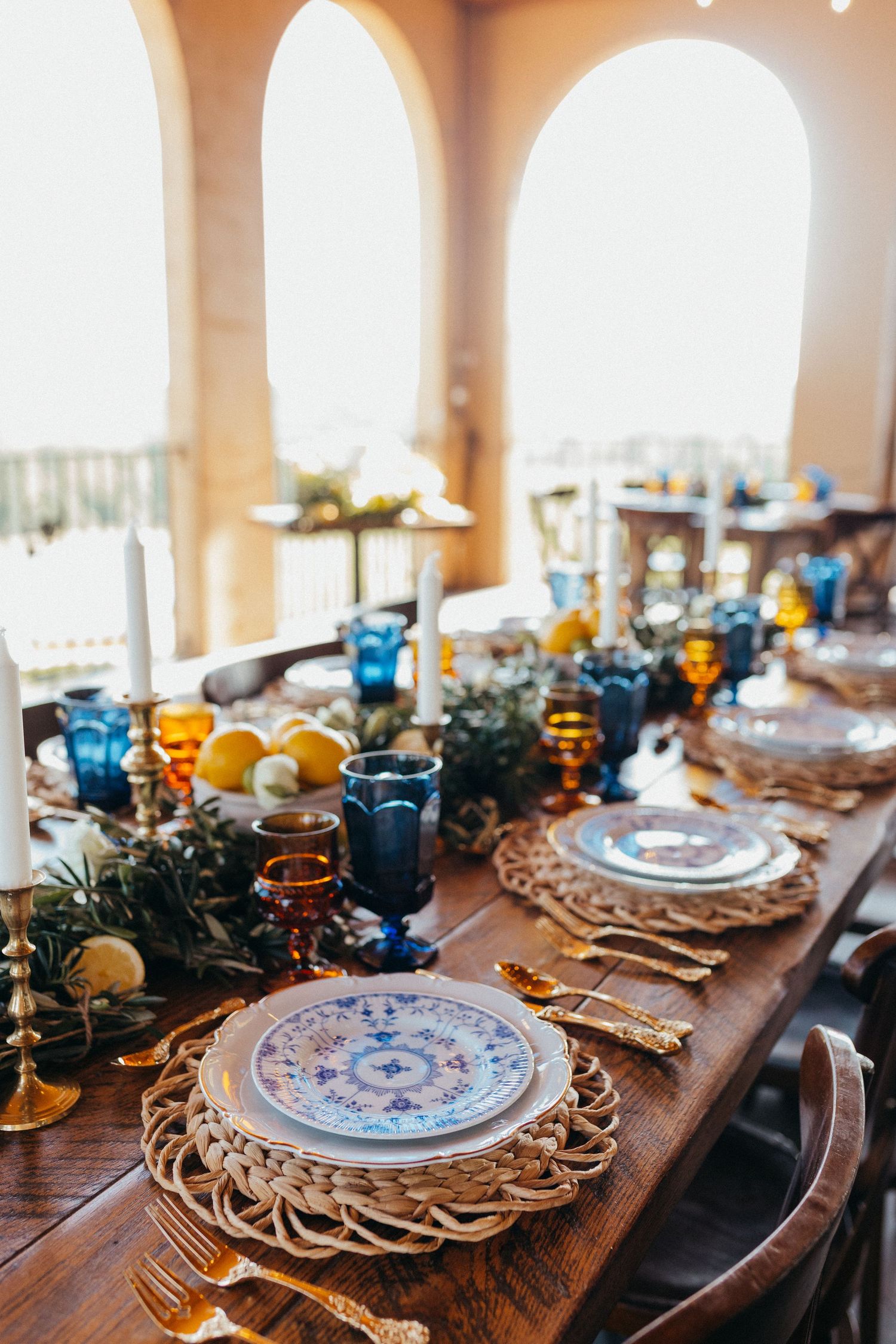 Fresh lemons and citrus fruits arranged on rustic wooden surface with white flowers and green foliage.